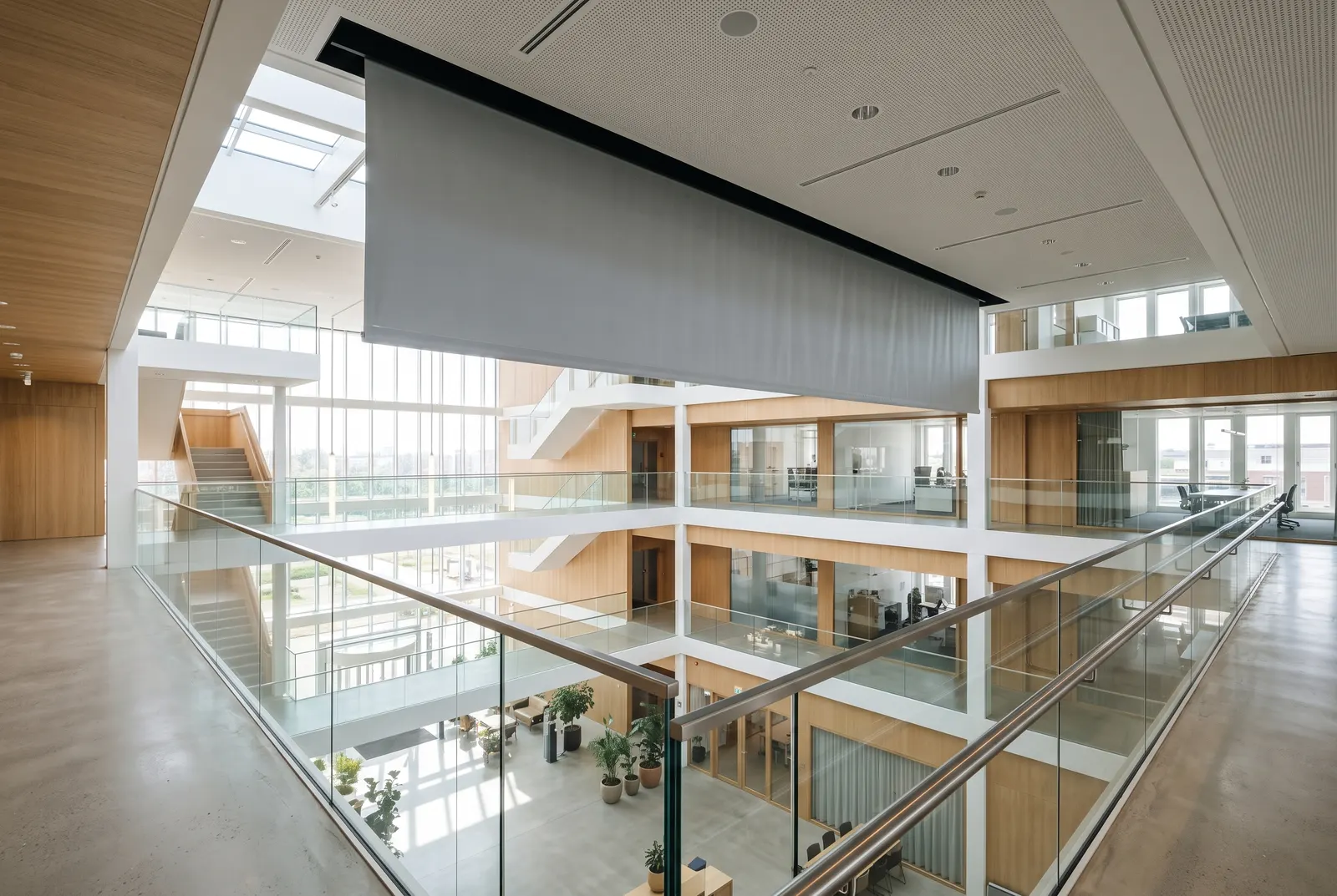 Rookwerend scherm dat automatisch sluit boven een atrium in een modern kantoorgebouw